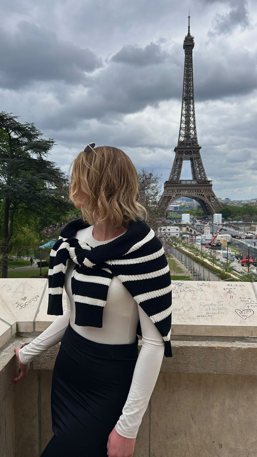 Vor dem Eiffelturm in Paris, gestreifter Strickpullover über den Schultern