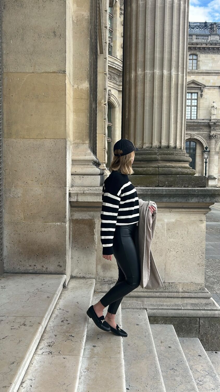 Im Säulengang des Louvre in Paris, gestreifter Pullover und Cap
